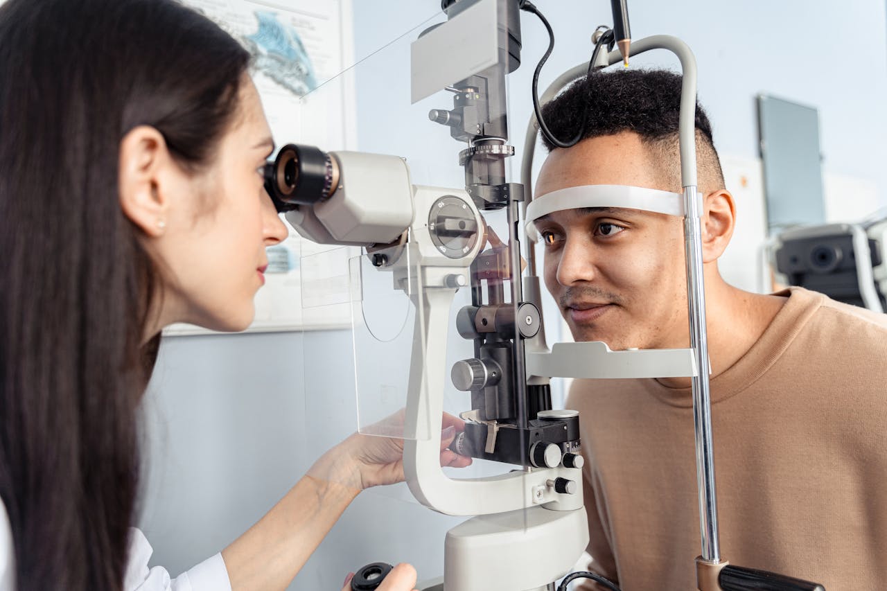 Optometrist examining a patients eyes with specialized equipment in a clinic setting.