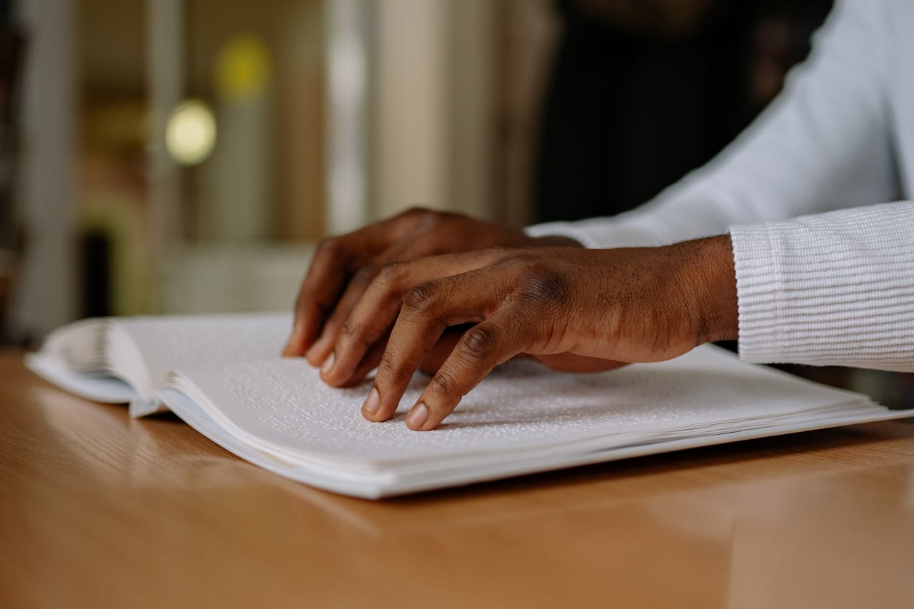 A person reading Braille with focused hands on textured paper indoors.