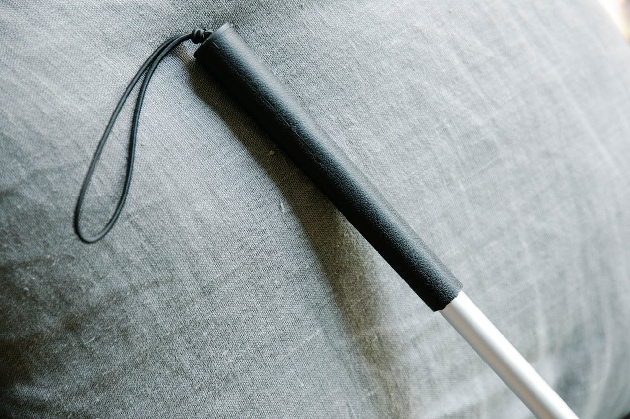 Detailed view of a white cane against a textured fabric background, symbolizing support for the visually impaired.